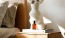 a vase with cotton stems on a bedside table